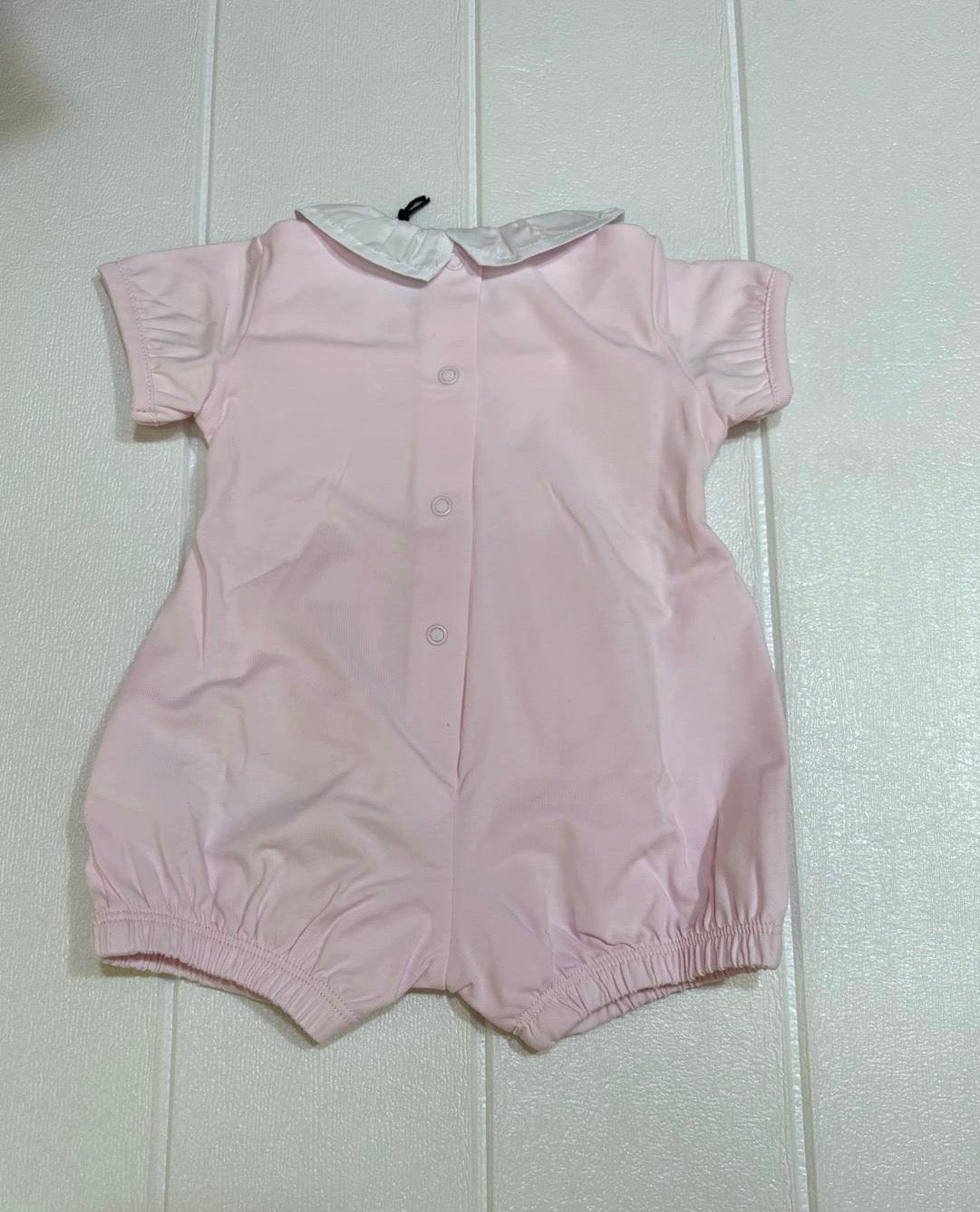 Pagliaccetto rosa con colletto bianco, ricamo in contrasto.