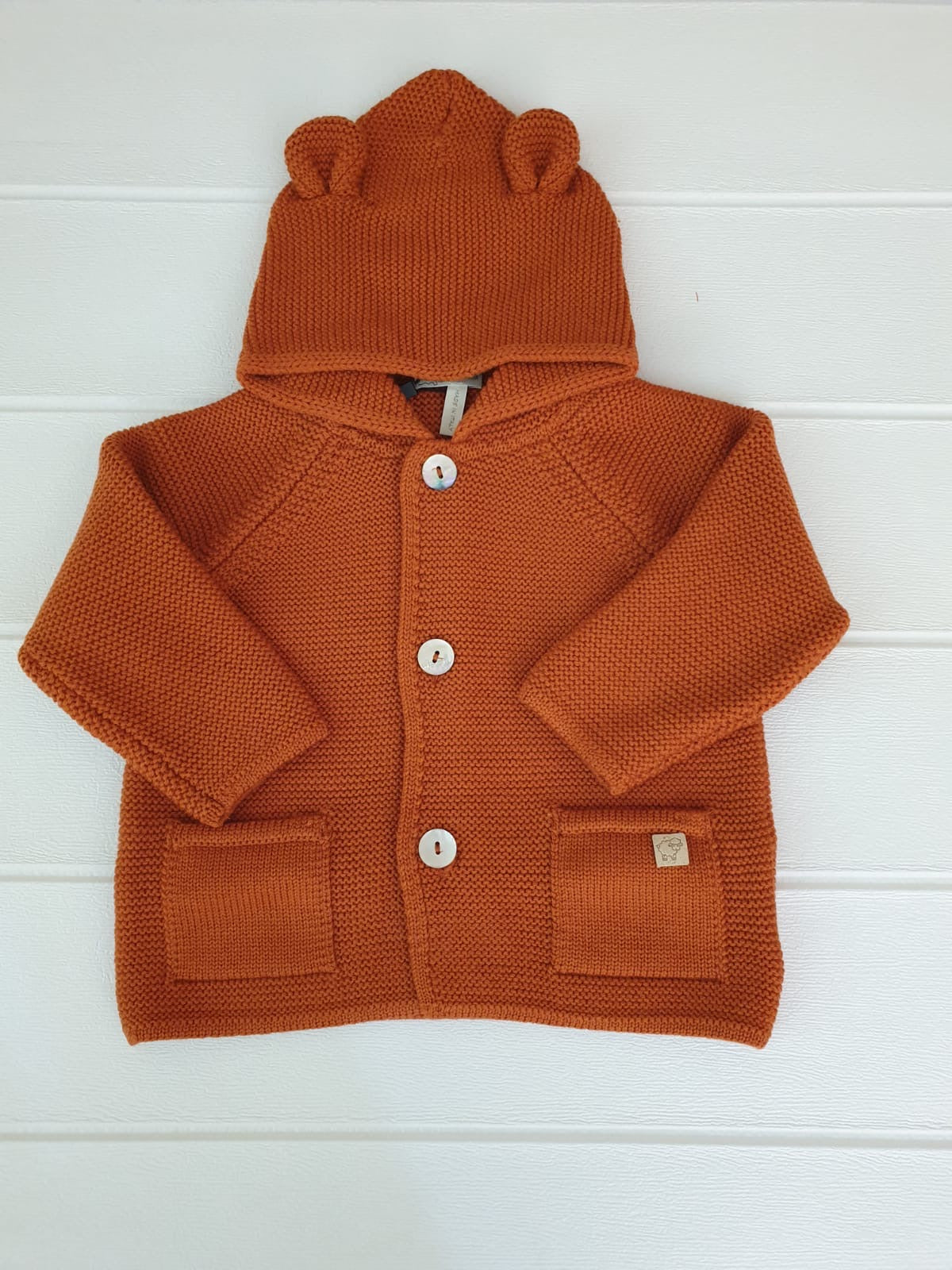 Cappottino con orecchie nel colore zucca, realizzato in pura lana Merino.