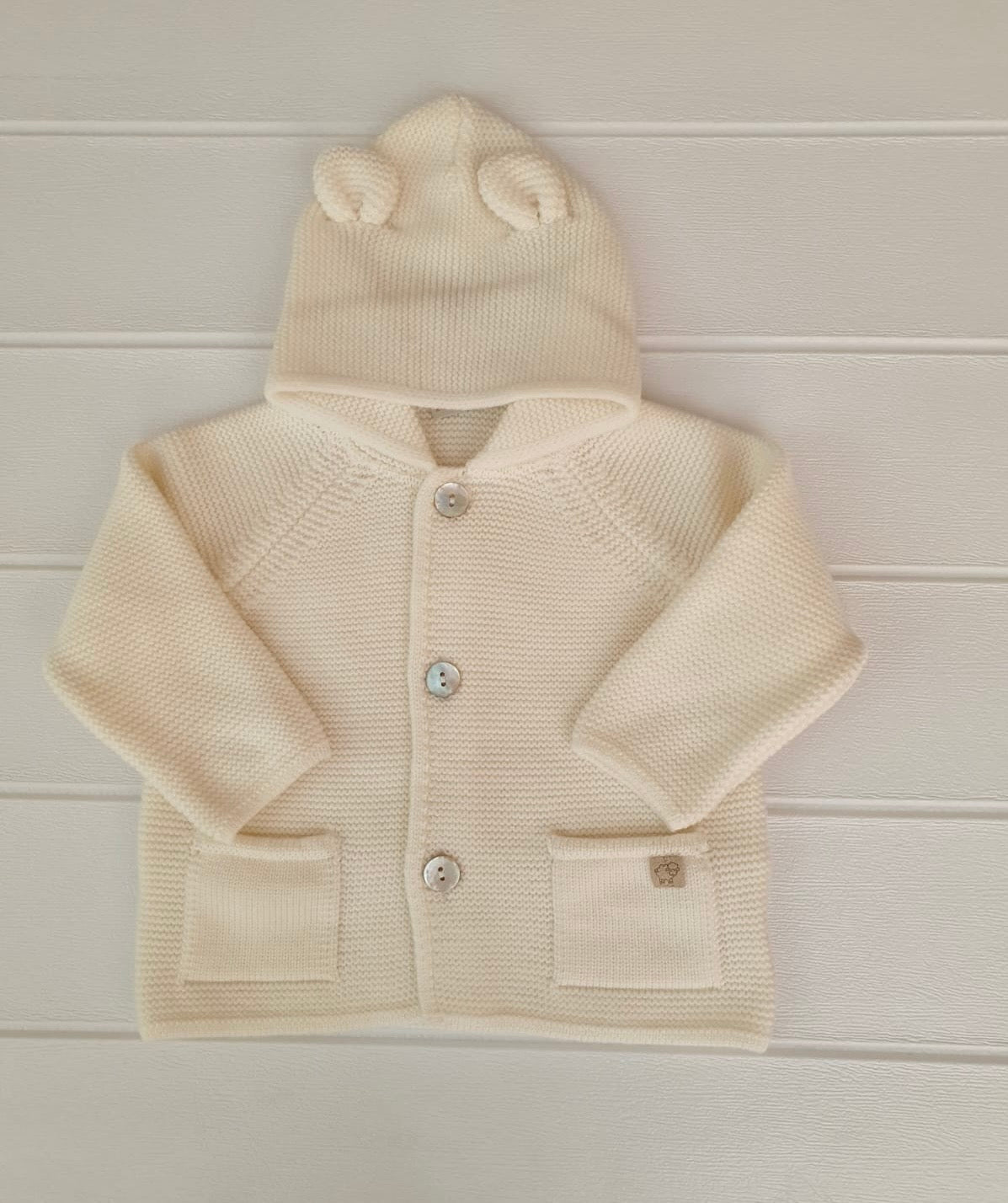 Cappottino con orecchie in pura lana Merino, nel colore panna.